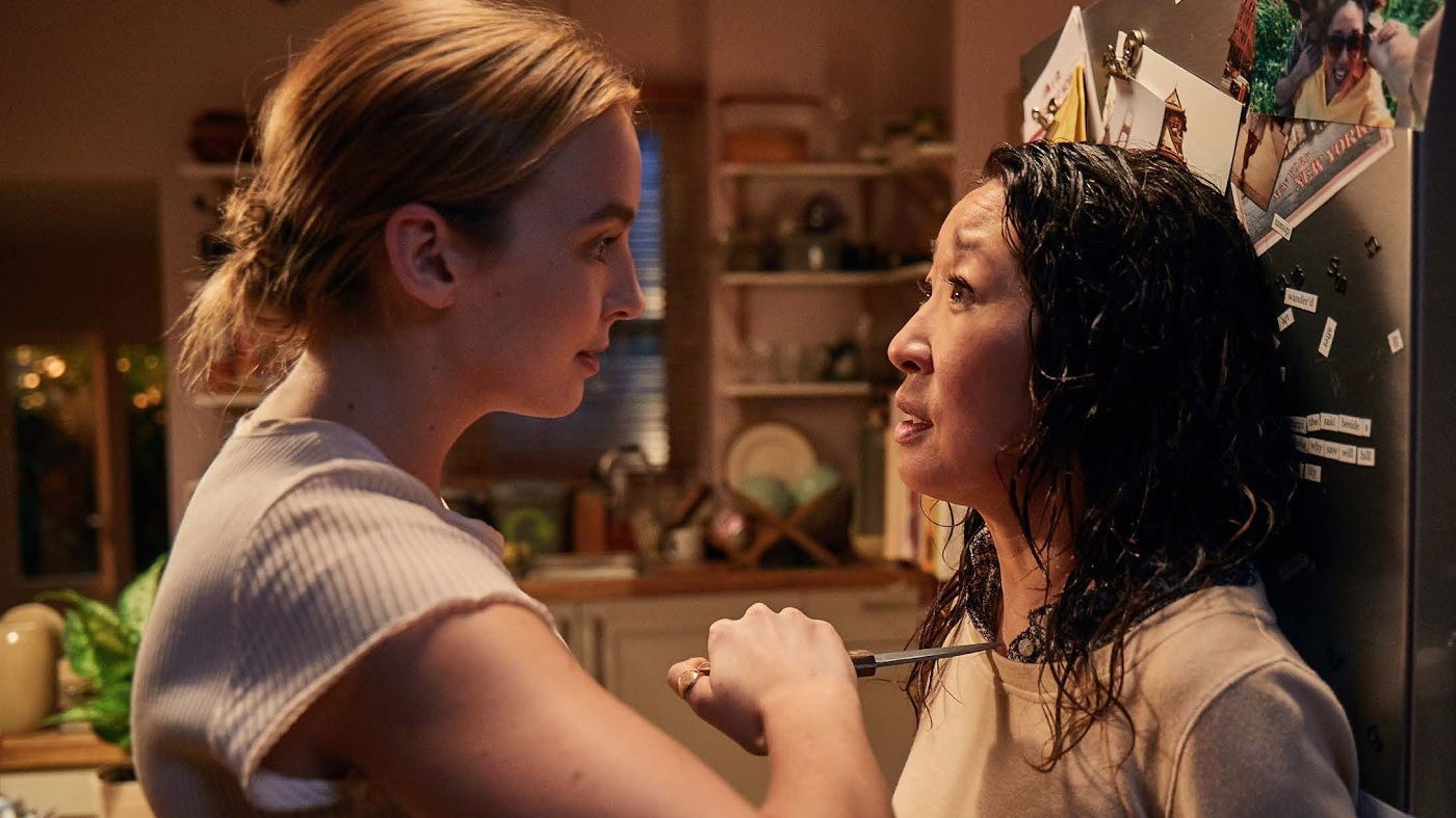 Mezzibusti di Jodie Comer e Sandra Oh all'interno di una cucina. Jodie Comer minaccia Sandra Oh con un coltello