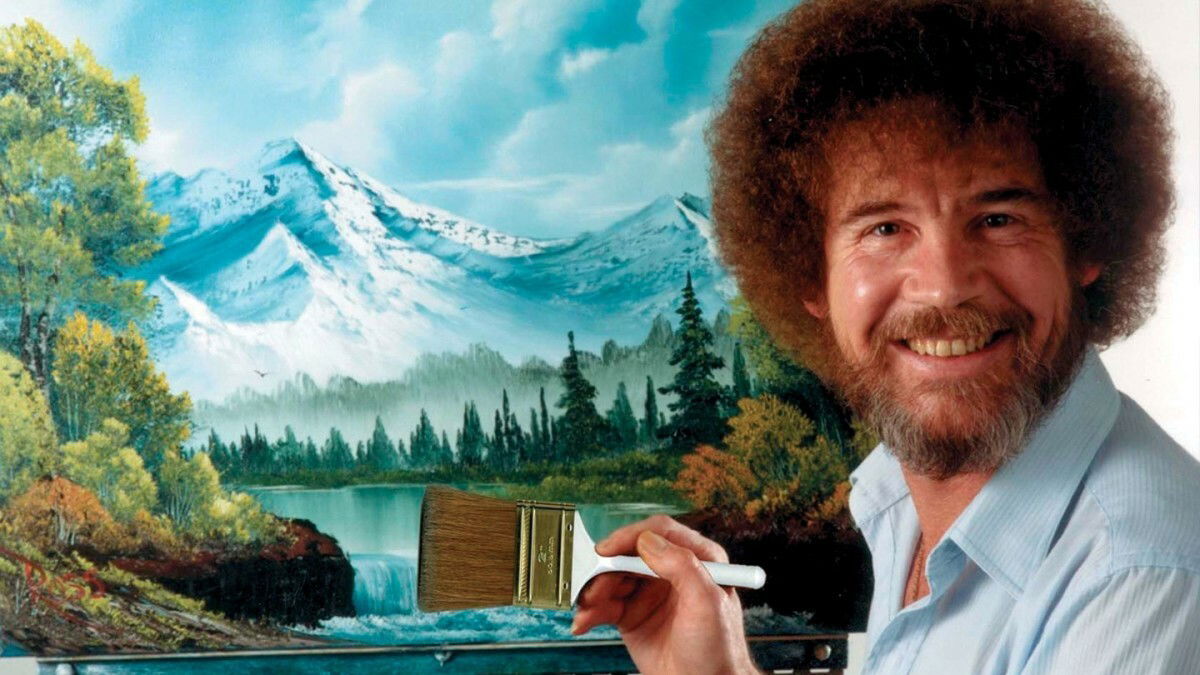 Clicca per vedere l'immagine originale Bob Ross sorridente con uno dei suoi dipinti