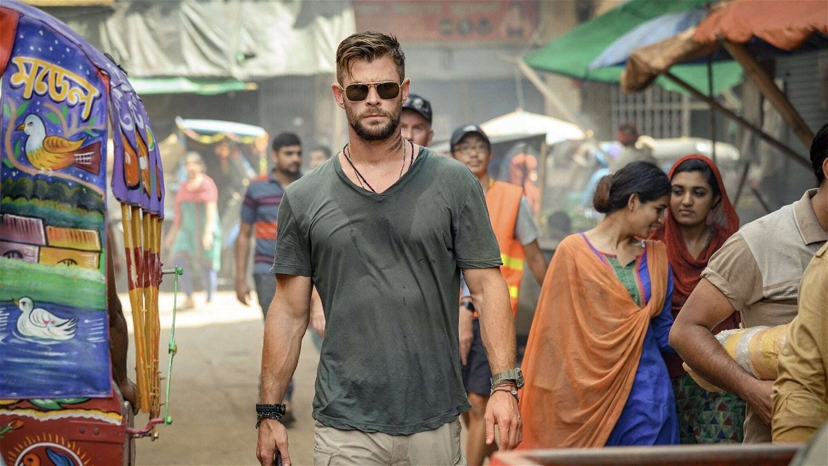 Mezza figura di Chris Hemsworth che attraversa una strada in India in una scena del film