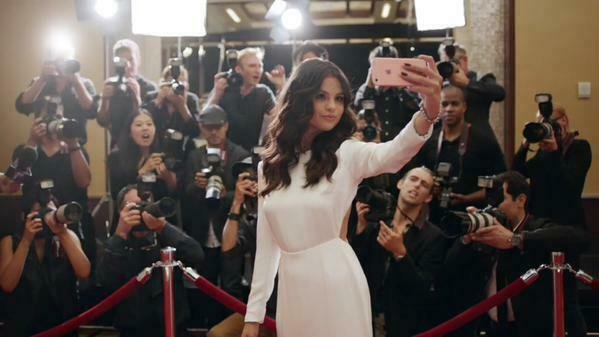 Selena Gomez si scatta un selfie sul red carpet con alle spalle i fotografi