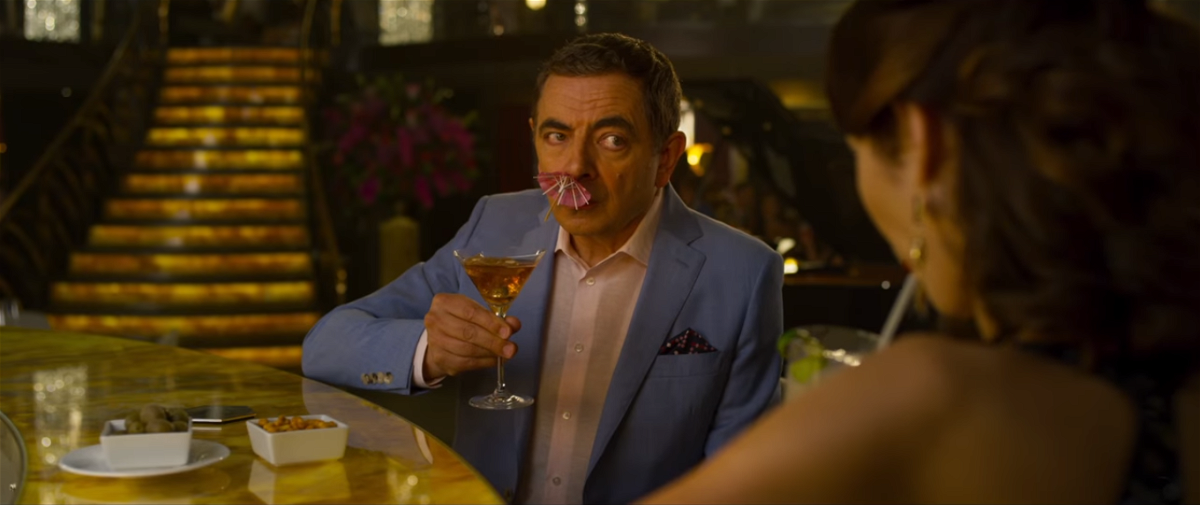 Rowan Atkinson con un ombrellino da cocktail nel naso