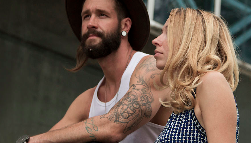 Un uomo tatuato di profilo con un gioiello Krato Milano nella barba