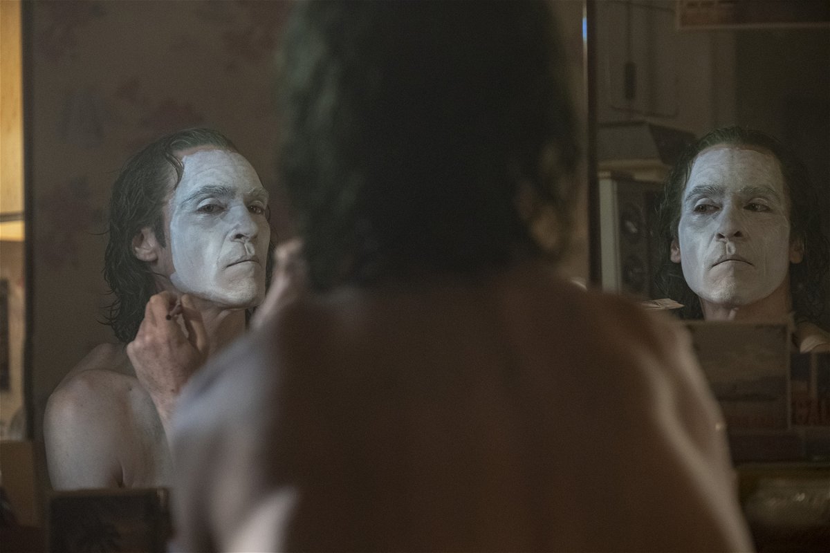 Joaquin Phoenix si trucca da clown in una scena del film Joker