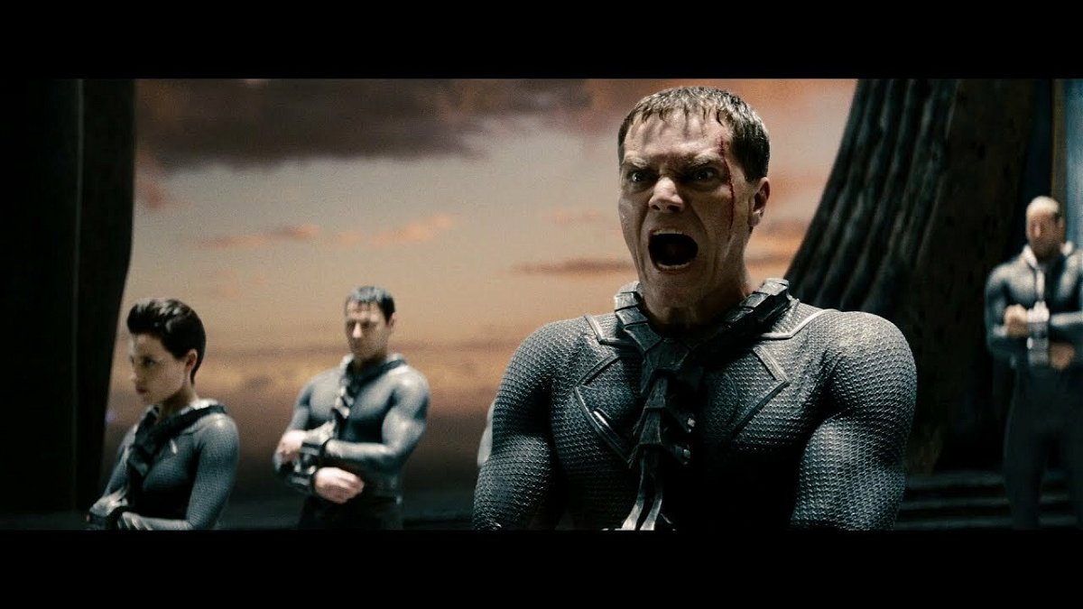 Mezzobusto di Michael Shannon urlante in tuta nera e altri personaggi sullo sfondo kryptoniano
