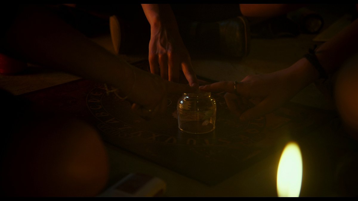 Le mani di Veronica, Rosa e Diana seguono il puntatore della tavoletta Ouija