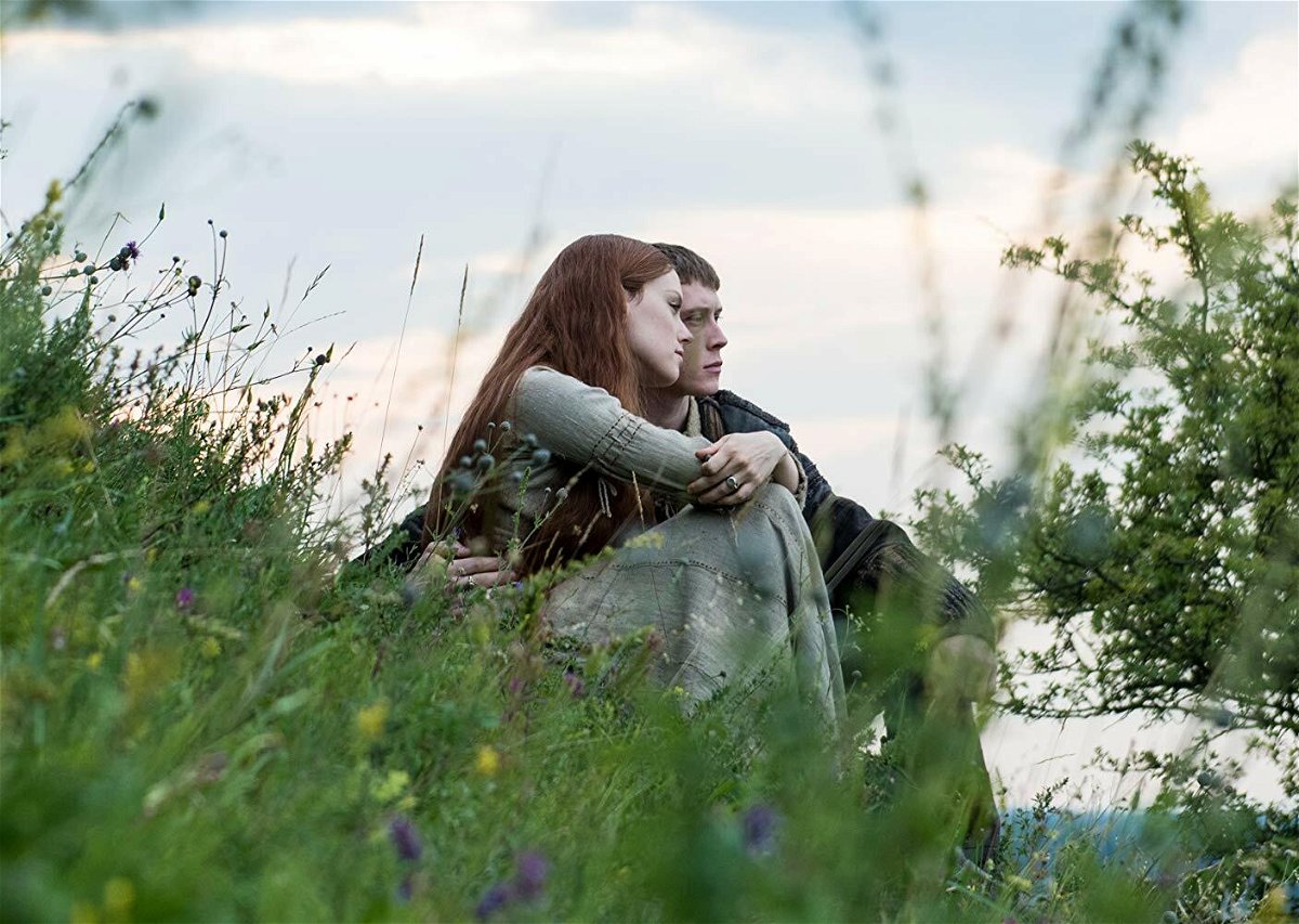 Daisy Ridley (Ofelia) e George MacKay (Amleto) seduti sull'erba in una scena del film
