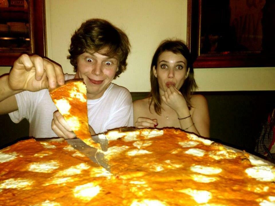 Emma Roberts ed Evan Peters davanti a un'enorme pizza