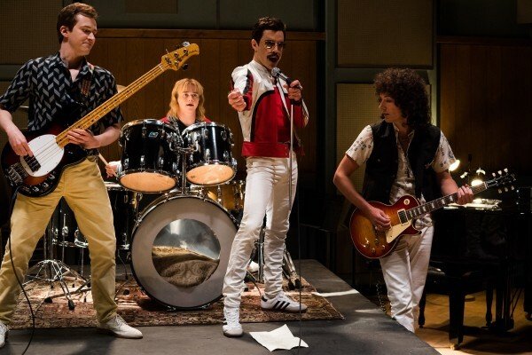 Figure intere dei quattro protagonisti del film nei panni di John Deacon, Roger Taylor, Freddie Mercury e Brian May, sul palco