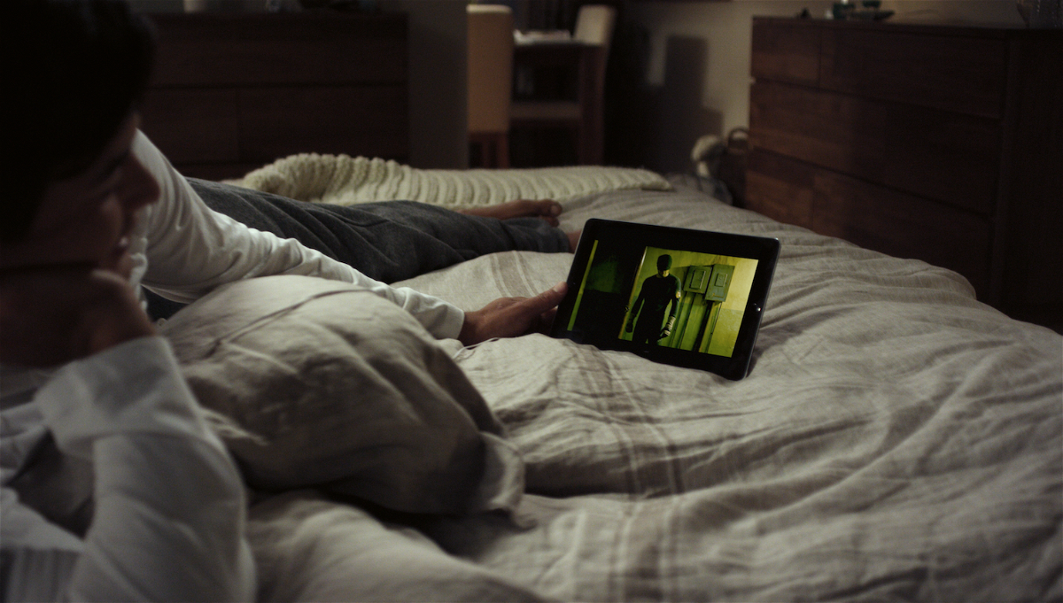 Un ragazzo sdraiato sul letto guarda una serie su un tablet
