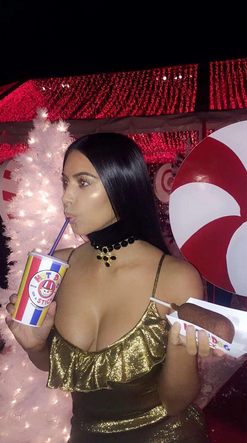 Kim Kardashian con in mano un hot dog alla festa di Natale