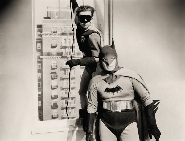 Batman in piedi in un appartamento, mentre Robin entra dalla finestra