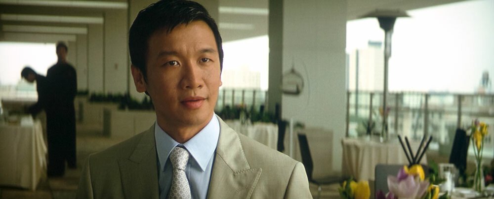 L'attore Chin Han in giacca e cravatta nei panni di Lau nel film Il Cavaliere Oscuro