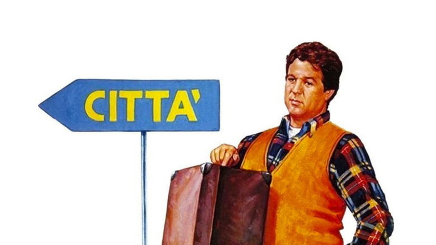 Renato Pozzetto con una valigia seduto su un maiale accanto al cartello città